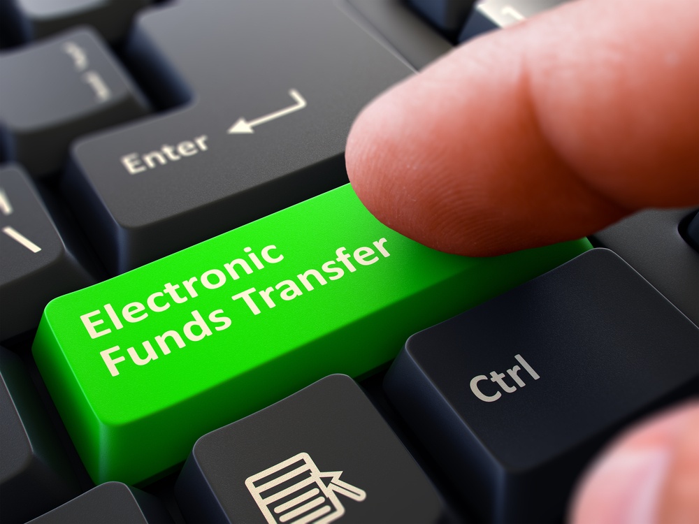 One Finger Presses Green Button Electronic Funds Transfer on Black Computer Keyboard. Closeup View. Selective Focus..jpeg